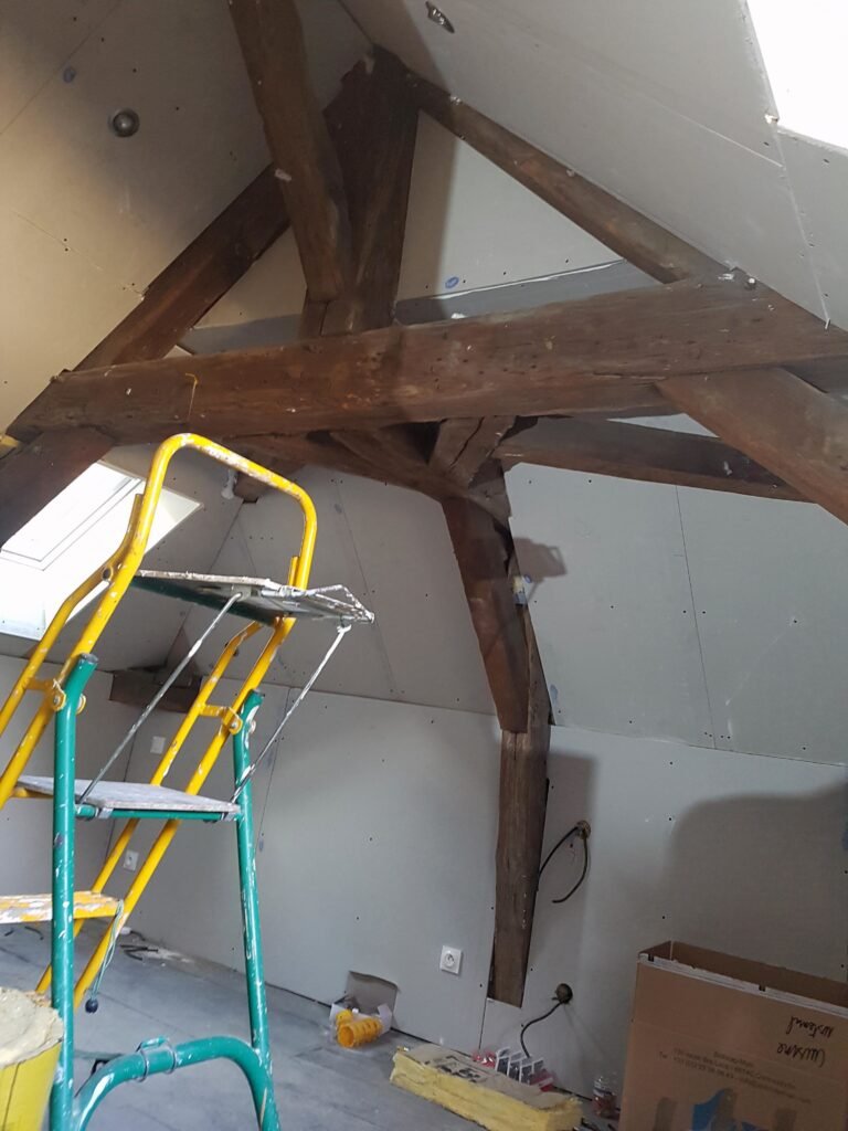 travaux de placo en cours dans des combles avec poutres apparentes conservées