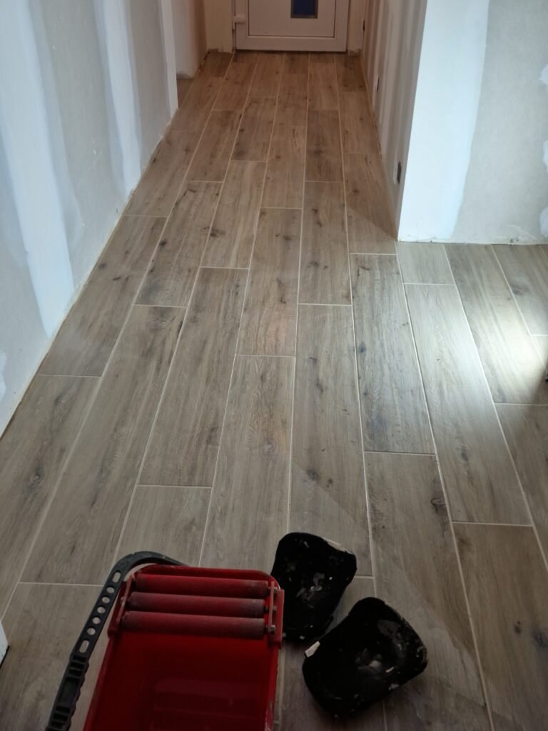 détail de pose de carrelage imitation bois dans un couloir rénové