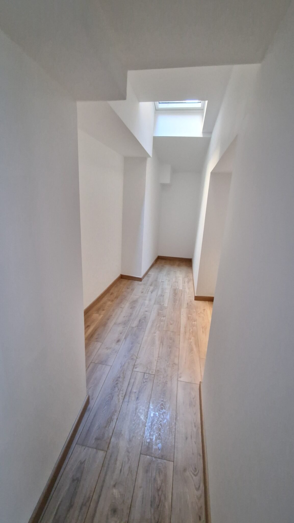 couloir rénové avec sol effet bois et finitions blanches après rénovation intérieure