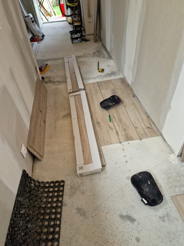 pose de carrelage effet bois en cours dans un couloir en rénovation