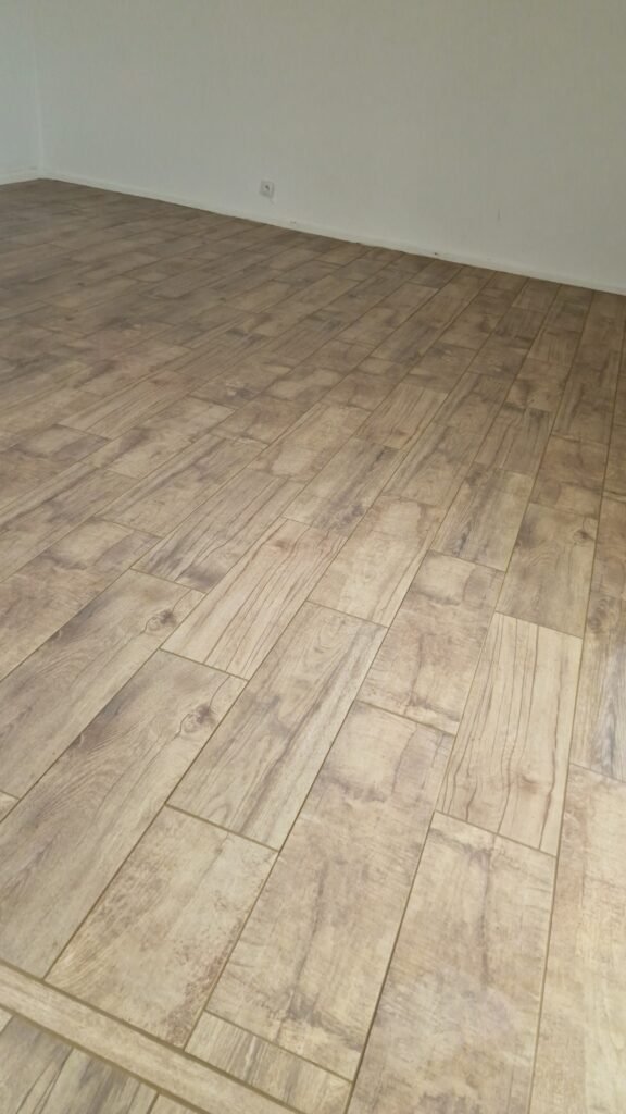 Vue d'ensemble du carrelage imitation parquet terminé dans une pièce rénovée à Moncy-Notre-Dame.