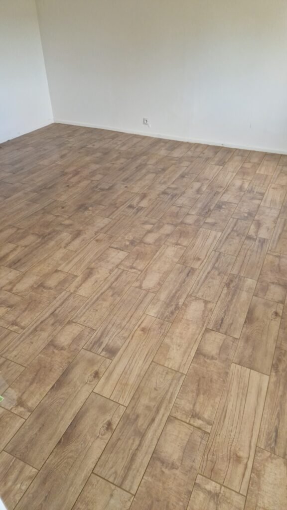 Détail du carrelage effet parquet avec joints couleur hêtre après rénovation d'un sol à Moncy-Notre-Dame.